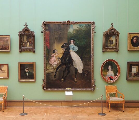 Картина в рамке, много портретов и пейзажей, покоящиеся на зеленой стене в музее, классическая живопись.